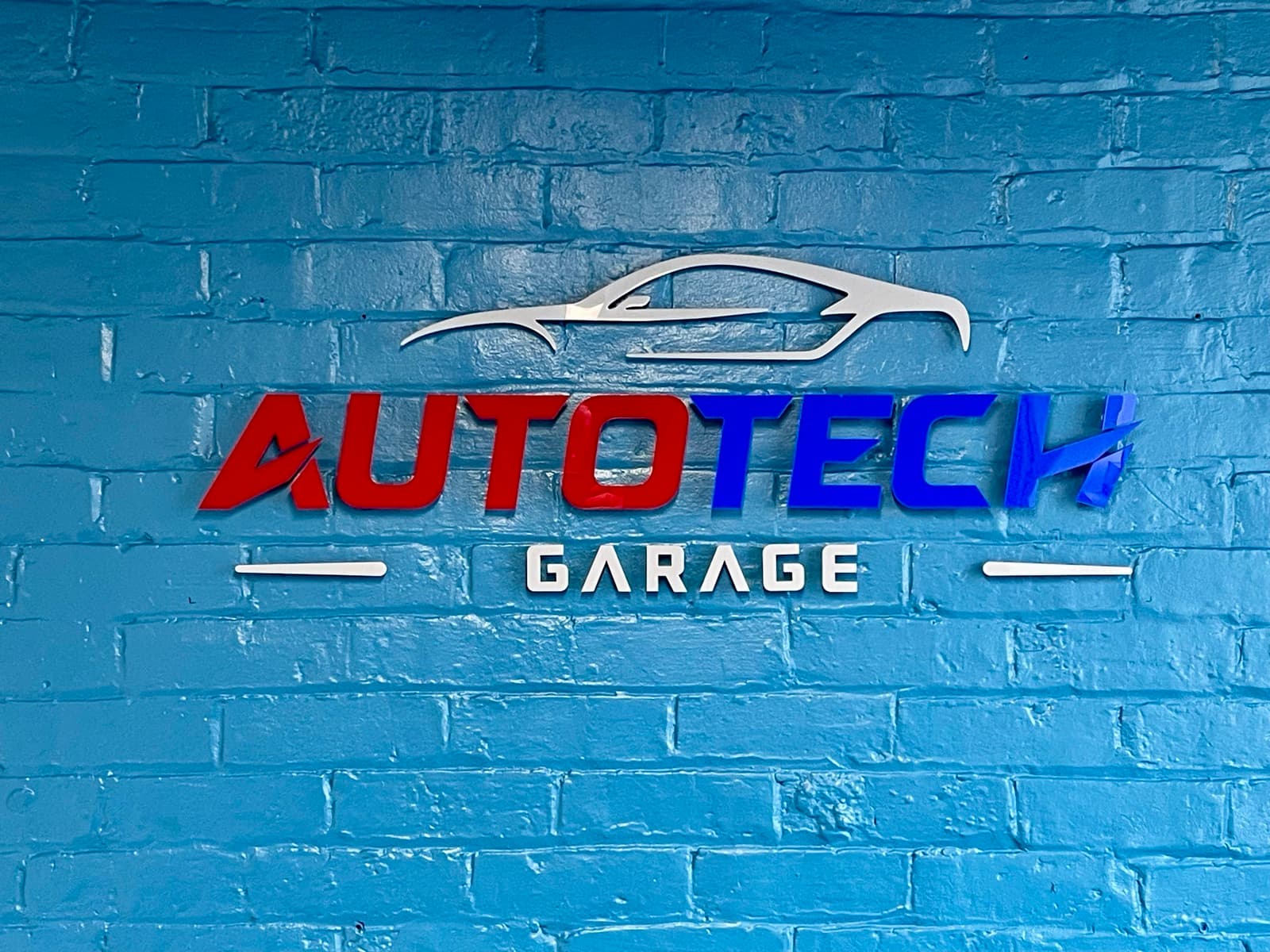 The garage's own sign, mounted square on the painted brick wall of the workshop.