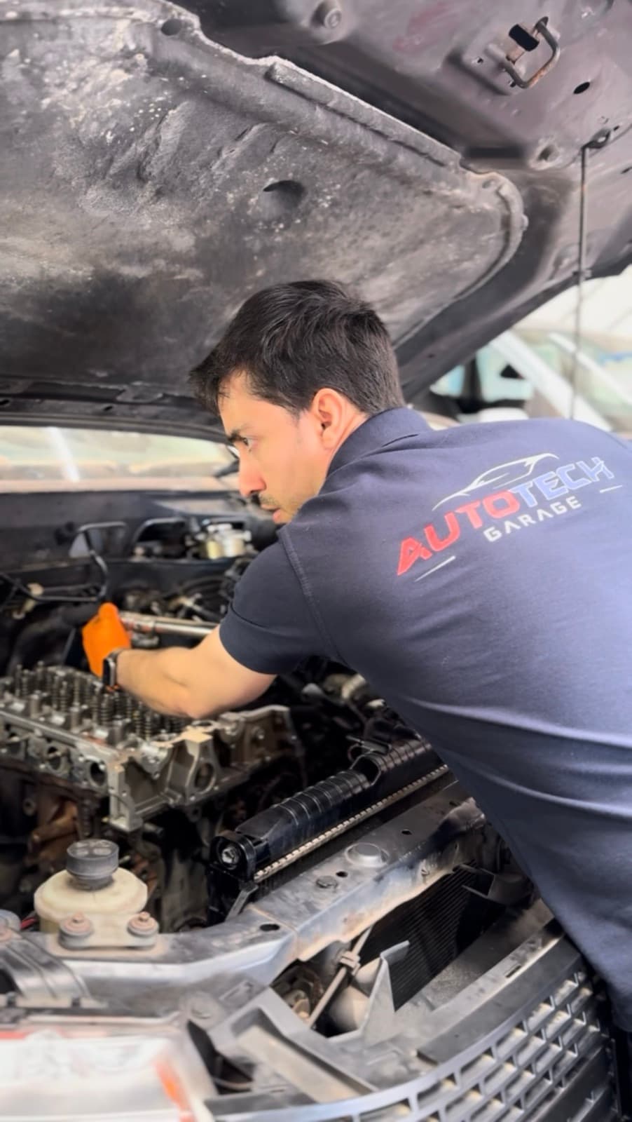An engine with its cylinder head removed, with a technician working on the valve train.