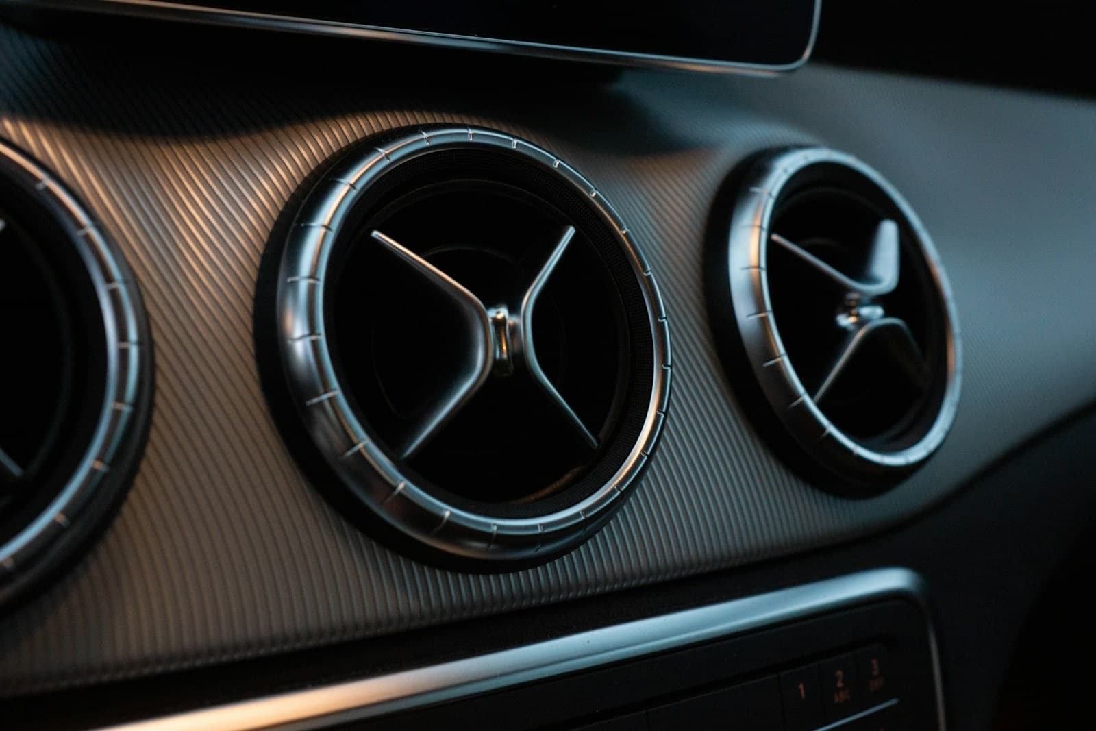 A close-up of circular dashboard air vents on a car facia.