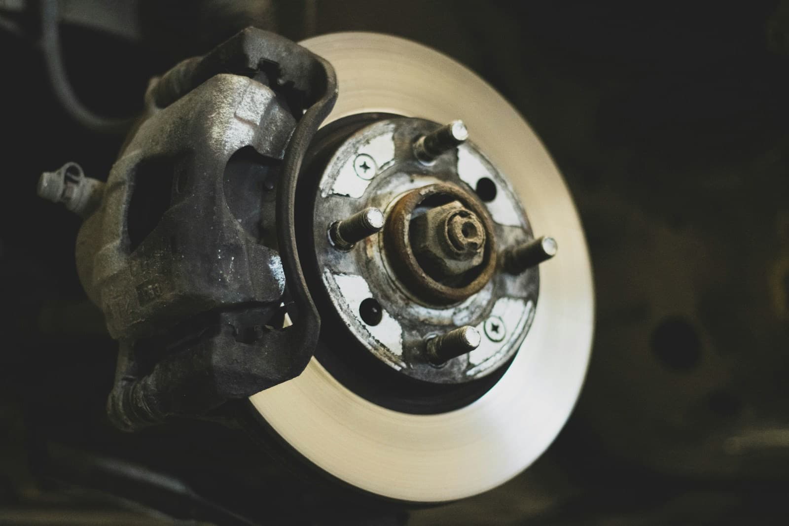 A close-up of a brake disc and caliper on a wheel hub, with the wheel removed.