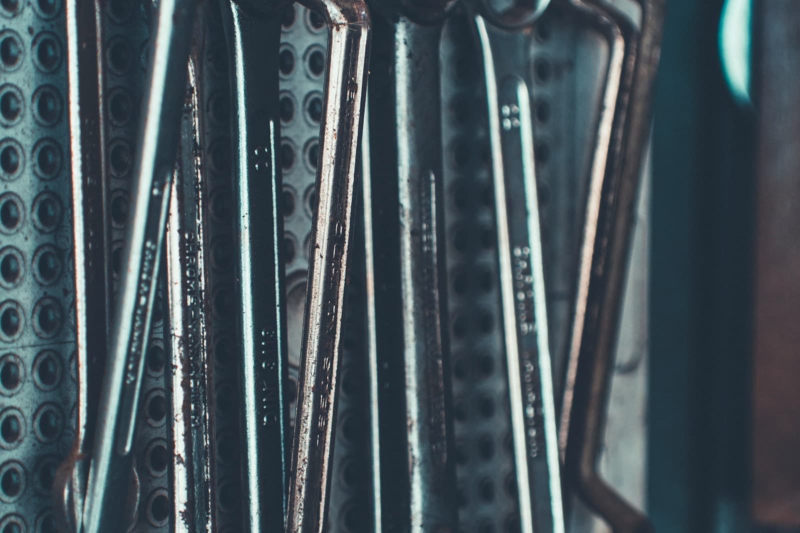A row of combination spanners hanging on a perforated steel tool board.