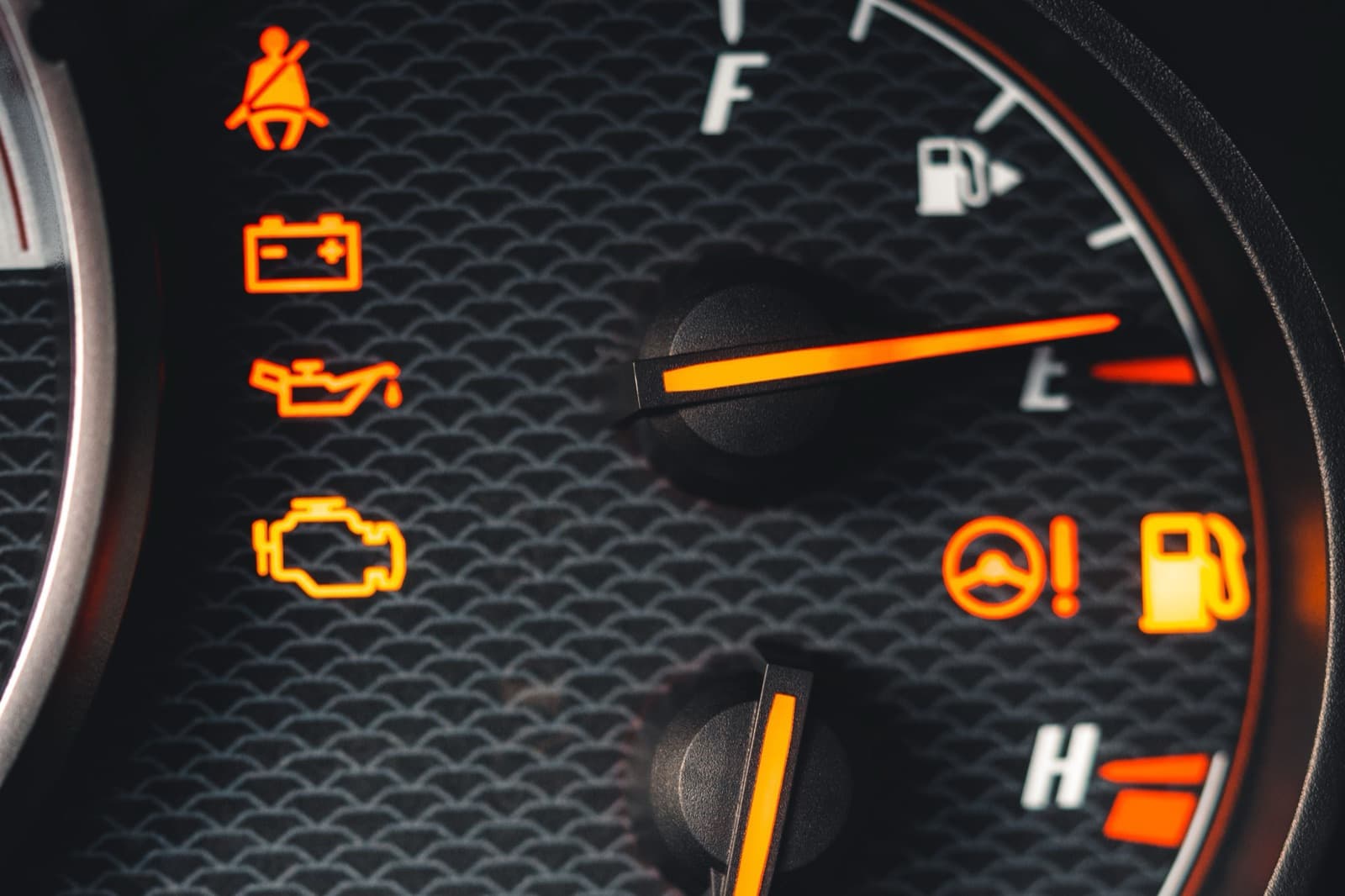 A close-up of an instrument cluster with the seat belt, battery, oil pressure and engine management warning lights lit in amber.